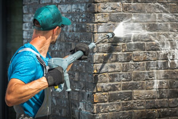 Man Cleaning Brick Surface with Water Preasure